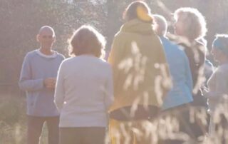 Yogalehrer leitet eine kleine Gruppe draußen in der Natur an