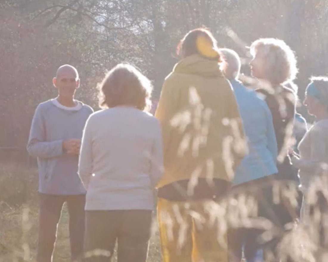 Yogalehrer leitet eine kleine Gruppe draußen in der Natur an